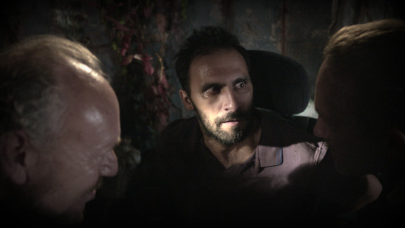 Stowaway Yusuf (Pietro Pace) is being questioned by the two tramps Frank (Max Gold) and Garrat (Ben Craze). / n.a.
